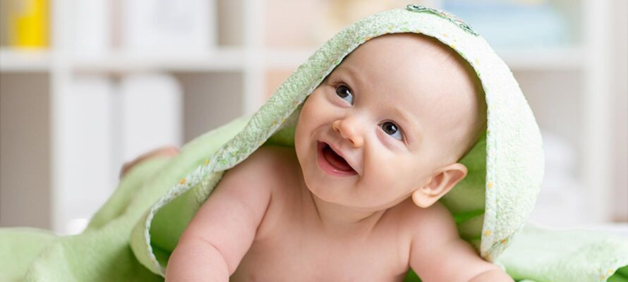 am Bauch liegendes Baby in hellgrünes Handtuch gewickelt