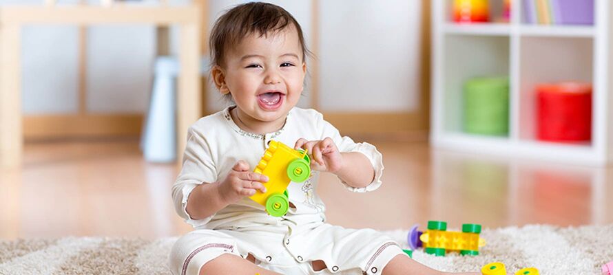 am Boden sitzendes Baby mit Spielzeug