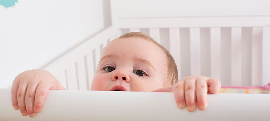 Baby schaut aus dem Gitterbett