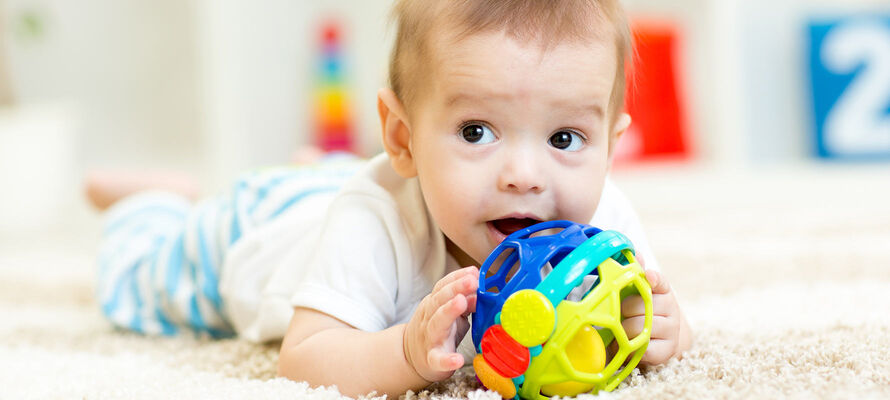 am Boden liegendes Baby mit Spielzeug