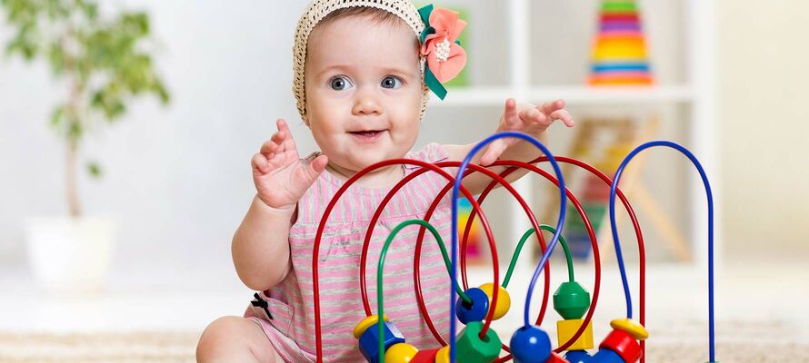 sitzendes Baby vor Spielzeug mit bunten Holzklötzen auf Spirale